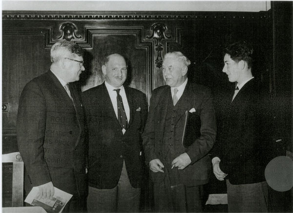 Copy of a photograph undated and unnamed showing four gentlemen standing. - one man is carrying a folder. One of the gentlemen is Osmond John